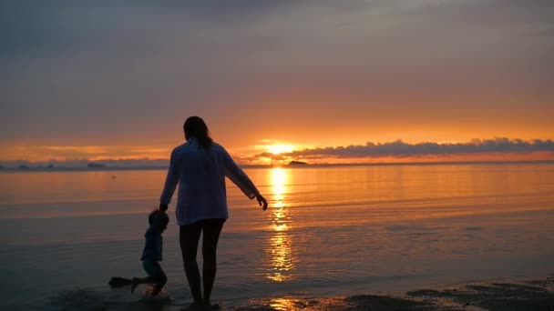 A menina com a criança ir para caminhadas e brincar na praia ao pôr do sol — Vídeo de Stock