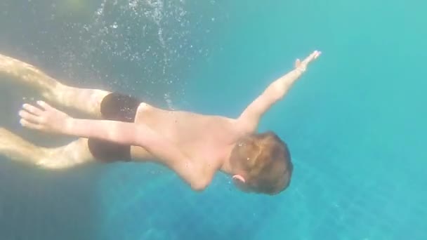 Glückliches Kind schwimmt genüsslich unter dem Wasser im Pool — Stockvideo