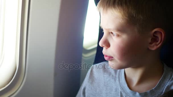 Un niño mirando por la ventana de un avión en un día soleado — Vídeo de stock