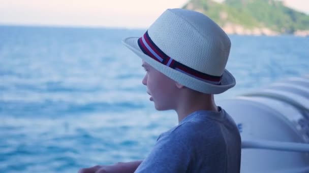 Uma criança fica em um navio flutuante e olha para a distância — Vídeo de Stock