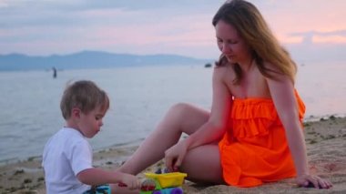 Bir çocuk kızla kum ile sahilde günbatımı anda çalış