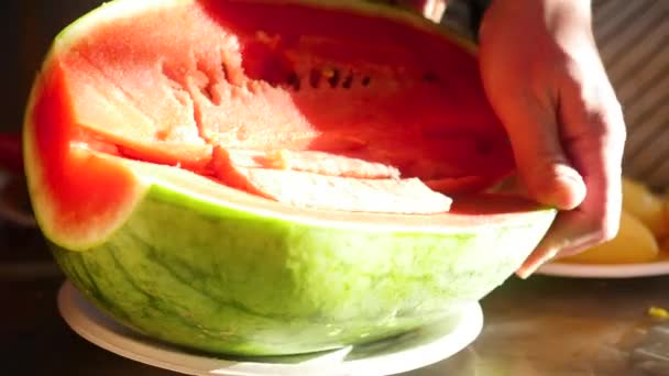 Mens hands cut the juicy red watermelon into pieces close-up — Stock Video