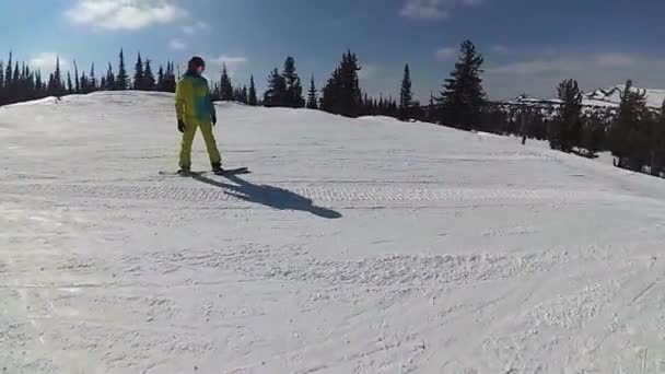 Ragazzo su uno snowboard scivolando lungo il pendio nella giornata di sole — Video Stock