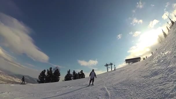 Щасливий хлопець на лижах ковзає по схилу в сонячний день — стокове відео