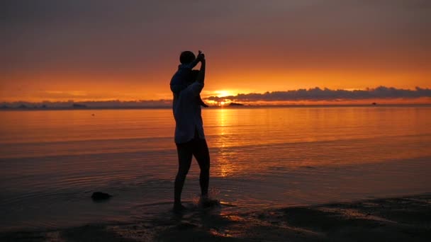 Das Mädchen mit dem Kind spazieren gehen und bei Sonnenuntergang am Strand spielen — Stockvideo