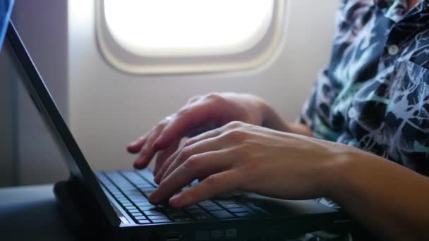 Tipo trabajando en el portátil en el avión cerca de la ventana — Vídeos de Stock