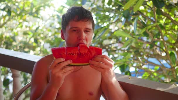 El tipo come una sandía jugosa dulce en un día caluroso de verano. — Vídeos de Stock
