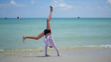 Çocuk jimnastik sahilde güneşli bir günde yapıyor