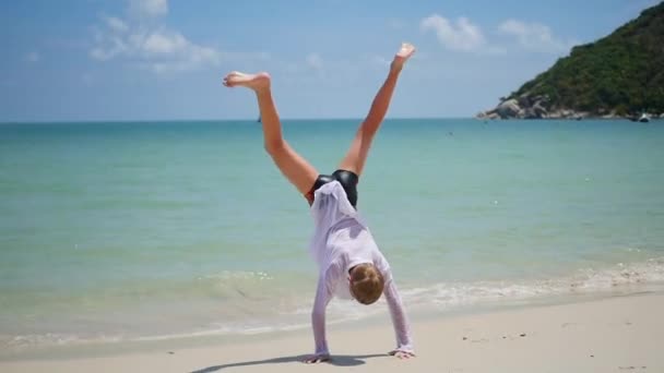 Dítě dělá gymnastiku na pláži za slunečného dne — Stock video