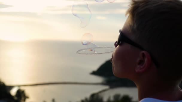 De jongen is het maken van zeepbellen. Close-up. Panoramisch uitzicht. Zonsondergang — Stockvideo