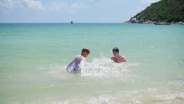 Счастливый парень и ребенок играют делает всплески в море — стоковое видео