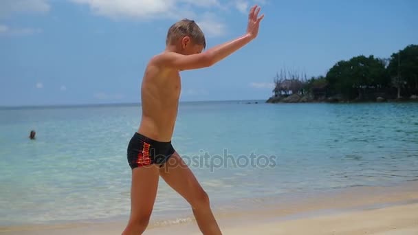 Το παιδί κάνει τη γυμναστική στην παραλία μια ηλιόλουστη ημέρα — Αρχείο Βίντεο