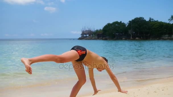 Το παιδί κάνει τη γυμναστική στην παραλία μια ηλιόλουστη ημέρα — Αρχείο Βίντεο