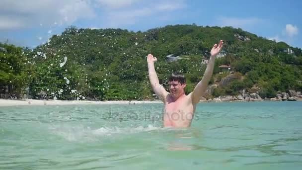 Счастливый парень распыляет воду в открытом море — стоковое видео