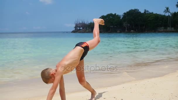 Gyerek csinál gimnasztika a tengerparton, egy napsütéses napon — Stock videók