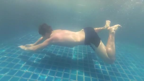 Pływa sobie szczęśliwy facet z radości pod wodą w basenie — Wideo stockowe