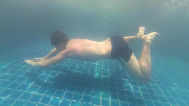 Happy guy swims with enjoyment under the water in the pool — Stock Video