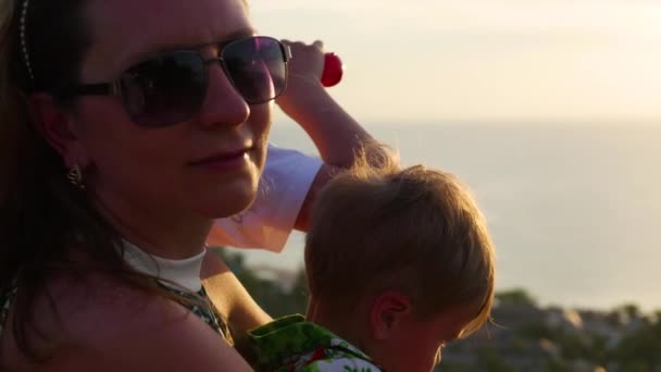 De familie kijkt naar de zee en de bergen vanaf een hoogte op zonsondergang tijd. Panoramisch uitzicht — Stockvideo