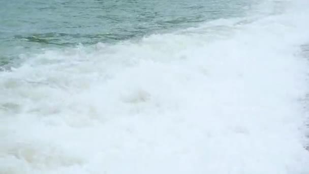 El niño se encuentra en la playa y está bañado en grandes olas marinas — Vídeo de stock