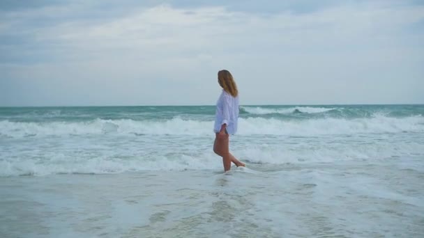 A young girl walks along the shore of the beach — Stock Video
