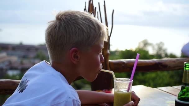 Молодий чоловік у кафе п'є коктейль на терасі. на відкритому повітрі — стокове відео
