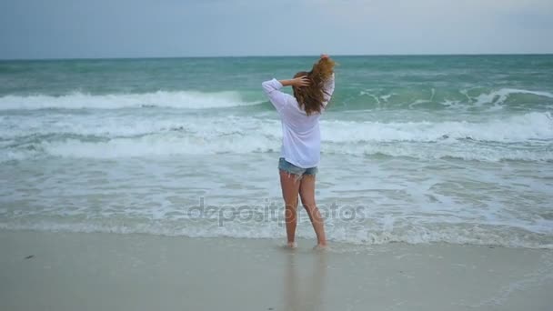 A young girl walks along the shore of the beach — Stock Video