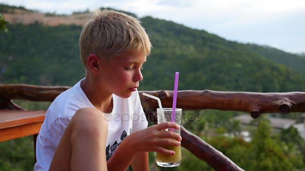 一个年轻男子在一家咖啡馆，在阳台上喝一杯鸡尾酒。户外活动 — 图库视频影像
