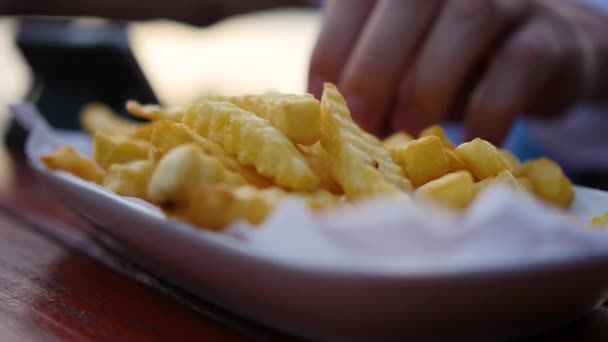 La main récupère les pommes de terre frites dans l'assiette. floue, gros plan . — Video