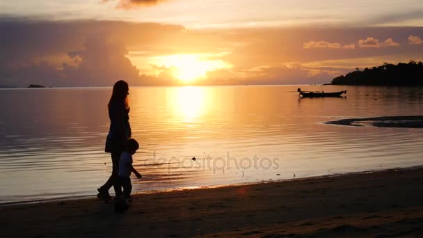 Dziewczyna z dziećmi iść na spacery i grać na plaży podczas zachodu słońca — Wideo stockowe