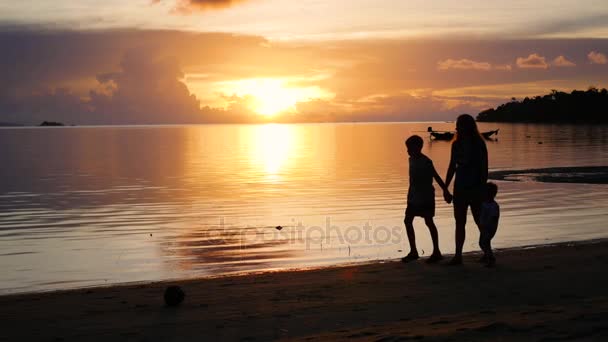 Девушка с детьми гуляет и играет на пляже во время заката — стоковое видео