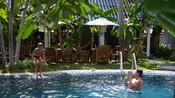 Un chico y un niño jugando a la pelota en la piscina. deportes al aire libre — Vídeo de stock