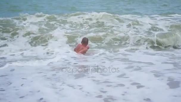 Счастливый ребенок купается в морских волнах в солнечный день — стоковое видео
