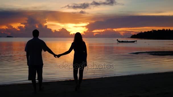 Amour garçon et fille marchant sur la plage à l'heure du coucher du soleil. Silhouettes — Video