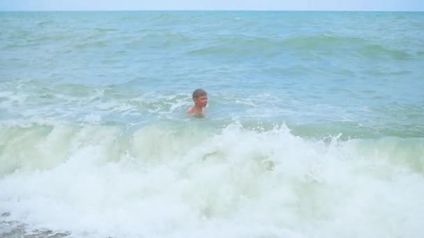 Criança feliz banha-se nas ondas do mar em um dia ensolarado — Vídeo de Stock