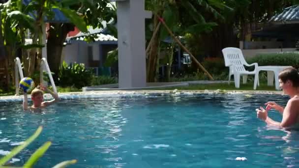 Un chico y un niño jugando a la pelota en la piscina. deportes al aire libre — Vídeo de stock