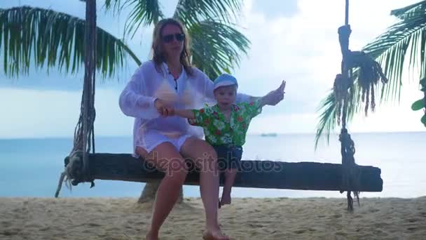 Une fille et un enfant se balançant sur une corde balançant sur la plage — Video