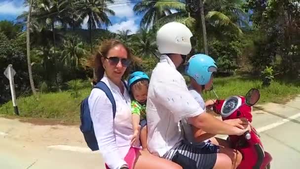 En lykkelig familie som kjører motorsykkel i tropene. En solskinnsdag. PHANGAN, THAILAND – stockvideo