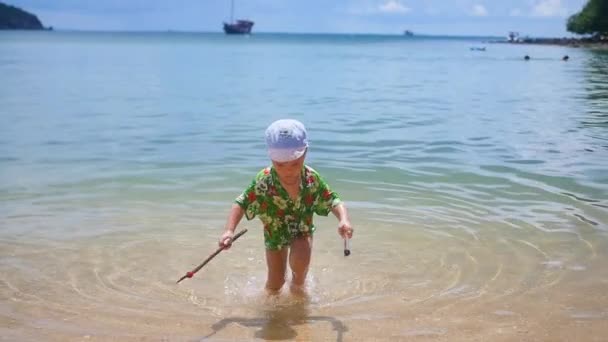 Un niño jugando en la arena de la playa en el día soleado — Vídeo de stock