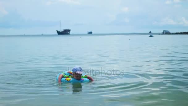 Ein glückliches Kind schwimmt in einem aufblasbaren Kreis im Meer — Stockvideo