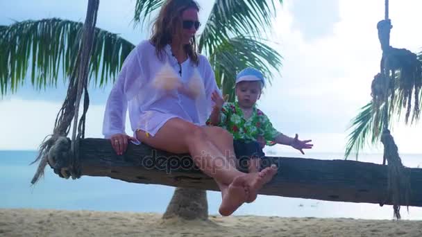 Девушка и ребенок, качающиеся на веревке на пляже. Тропический остров — стоковое видео