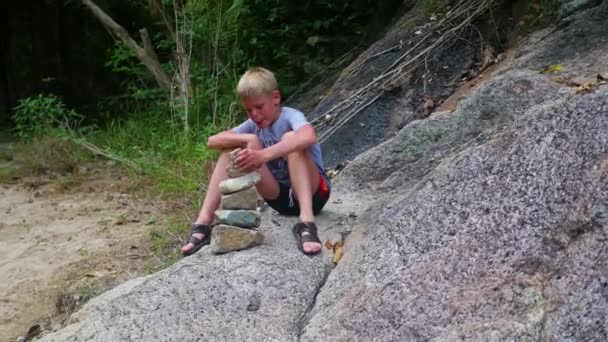 Un joven hace una escultura de piedras de equilibrio. Deportes al aire libre — Vídeo de stock