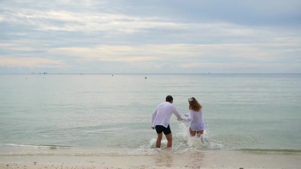 Boldog család kézenfogva fut végig a parton. Fut a víz, fröccsenő létrehozása — Stock videók