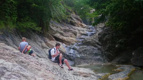 Familjen sitter på ett berg-strand. gör ett foto på en smartphone — Stockvideo