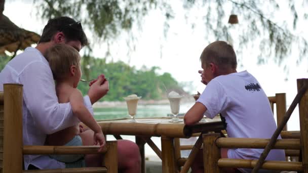 De familie eet ijs in een café op het strand — Stockvideo