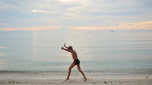 Bambino che fa ginnastica sulla spiaggia in una giornata di sole — Video Stock