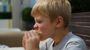 Bir çocuk bir pirzola ve peynirli çörek bir fast food Restoran yiyor.