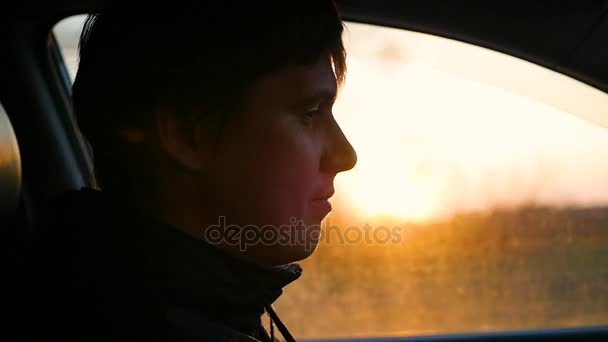 Хлопець водить машину в сонячний день. Час заходу сонця — стокове відео