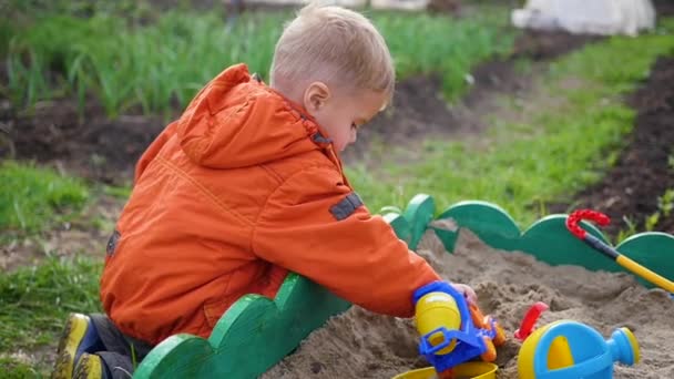 A criança brinca com os brinquedos na caixa de areia. close-up — Vídeo de Stock
