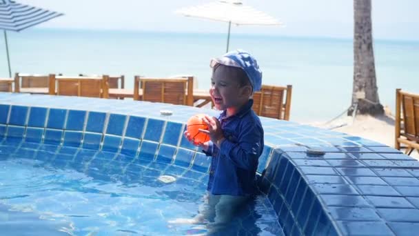 Klein kind speelt bal in het zwembad. Sport in de open lucht. — Stockvideo