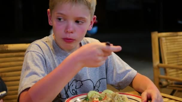 Kind speist in einem Café im Freien. Der Abend. Asiatisches Essen — Stockvideo
